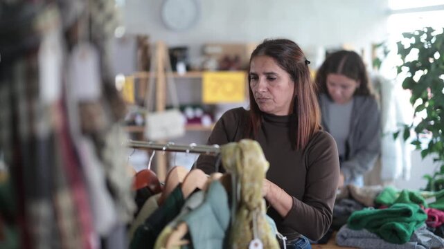Adult woman buyer choosing clothes for autumn and winter in clothing store