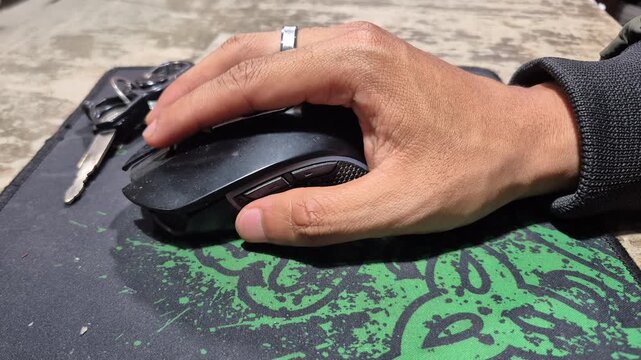 Close-up of a hand using a computer mouse on a desk pad, showing detailed finger movements and interaction.