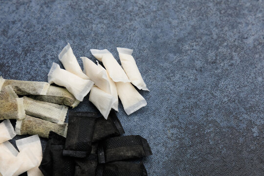 Different kinds of snus pouches and nicotine pads are arranged on a surface for display and consideration in a smoking product discussion