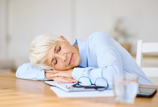 Portrait of a mature senior business woman sleeping at work in office