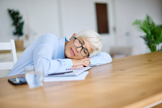 Portrait of a mature senior business woman sleeping at work in office
