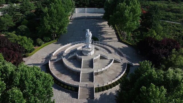 Aerial view of the circular plaza with monument statue at Rizhao Martyrs Cemetery surrounded by green trees and stone railings