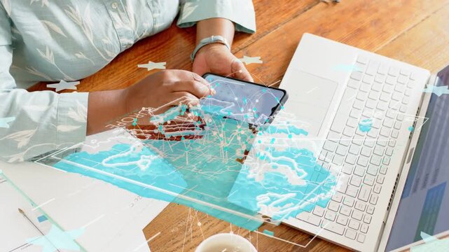 Woman picking up phone and swiping screen causing blue map overlay aligning with laptop for tech