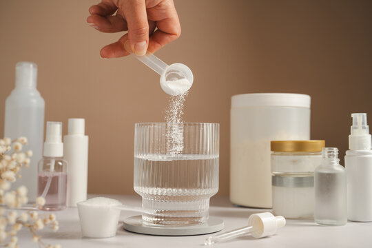 Woman adding collagen supplement to water alongside skincare products and self care routine