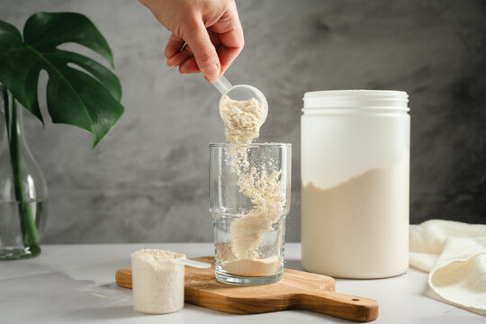 Protein powder being poured into glass, sports nutrition concept