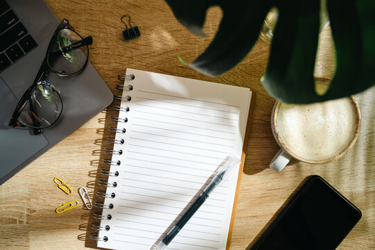 Home office workspace with notebook, coffee and smartphone on wooden desk, top view
