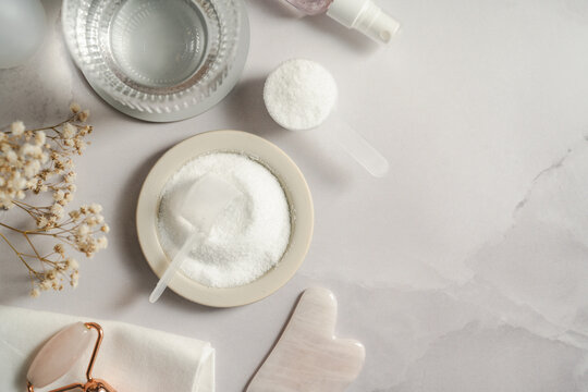 Collagen powder, skincare tools and wellness accessories flat lay with copy space