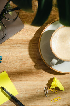 Coffee cup with blank sticky note on office desk, top view workspace mockup with copy space