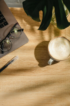 Home office workspace with open notebook, coffee and eyeglasses on wooden desk, top view with copy space