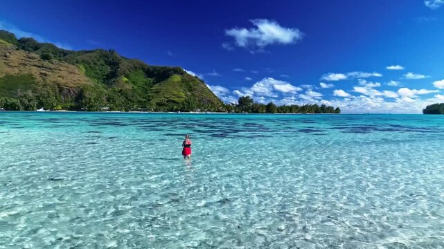 Woman walking in tropical turquoise lagoon in bora bora