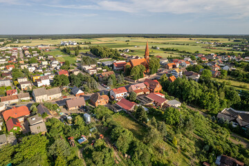 Widok z lotu ptaka na wieś Cekcyn w Puszczy Tucholskiej, w województwie kujawsko-pomorskim, Polska. Widoczny jest zabytkowy kościół, tradycyjne domy mieszkalne, pola uprawne oraz malowniczy krajobraz. © Marcin