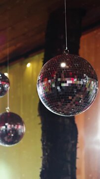 Vertical video. Hanging mirror disco balls rotating above wedding banquet tables.