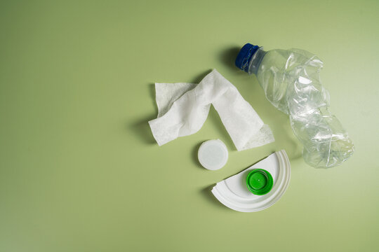 Plastic waste items on green background with copy space, recycling and environmental pollution concept