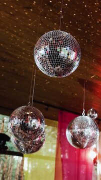 Vertical video. Ceiling mirror disco balls creating reflections at wedding restaurant.