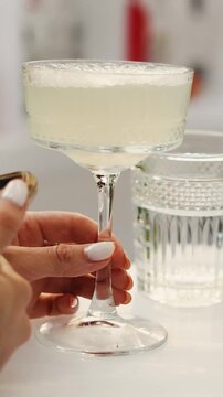 Vertical video. Cocktail glass in woman hand while using smartphone at outdoor wedding bar.