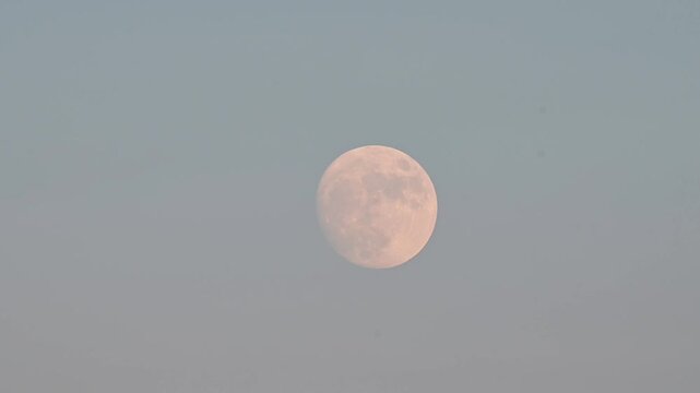 Moon at dusk illuminated clouds, movement at slow pace, close up, vivid background authentic video. Setting sun illuminated clouds