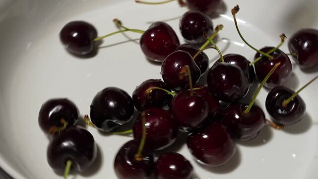 Fresh organic red cherries rotating and scattering, close up view