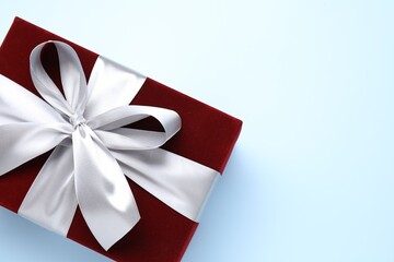 Fototapeta premium Beautiful velvet gift box on light blue background, top view. Space for text