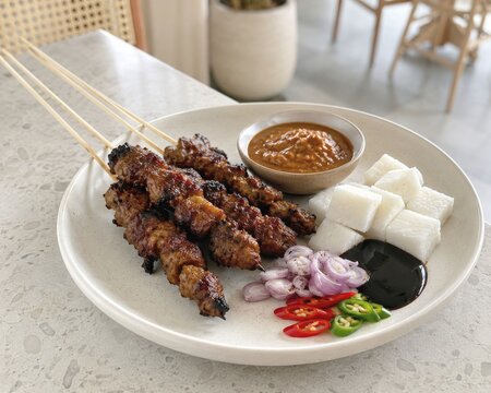  Sabroso Satay servido sobre hoja de pl&aacute;tano con salsa de cacahuete, salsa dulce, lontong, chalotas y chiles frescos, una especialidad cl&aacute;sica de la cocina indonesia.