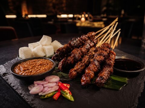  Tradicional Satay servido con salsa de cacahuete y salsa de soja dulce, acompa&ntilde;ado de lontong, chalotas y chiles frescos en una elegante presentaci&oacute;n gastron&oacute;mica.