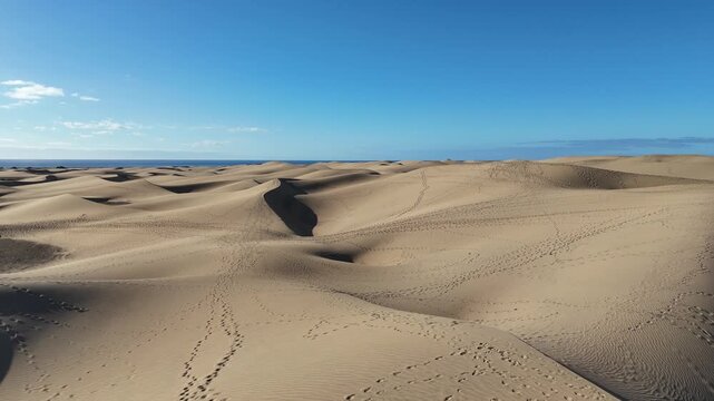 Aerial panorama flight over Maspalomas Dunes with footprints towards Atlantic ocean in Playa del Ingles on Canary Island Gran Canaria, Spain