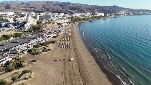 Aerial panorama flight over Maspalomas Dunes with hotels in Playa del Ingles, beach, Atlantic ocean and mountains on Canary Island Gran Canaria, Spain