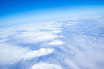 Naklejka premium Beautiful aerial view of soft white clouds stretching across the sky as seen from an airplane window during flight.