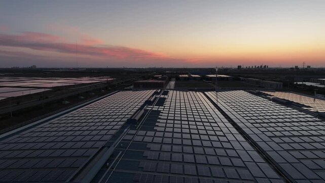 Solar photovoltaic array on industrial factory roof during sunset with vibrant sky