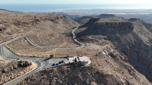Aerial panorama flight along road over viewpoint Mirador Degollada de las Yeguas towards Maspalomas and Atlantic Ocean on Canary Island Gran Canaria, Spain