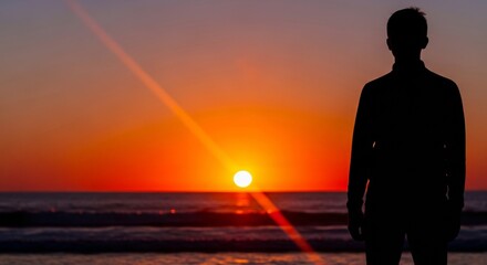 Fototapeta premium Man's silhouette against vibrant sunset ocean waves, sun rays creating dramatic light, symbolizing wellness and inspiration