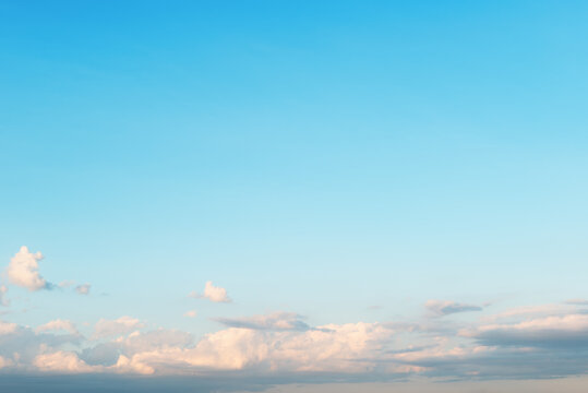 Beautiful blue sky background with soft pastel clouds near the horizon. Clear summer day sky background banner with copy space representing freedom, inspiration and serenity.