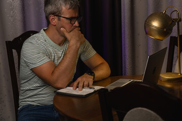 Obraz premium Freelancer works on laptop at home during evening hours