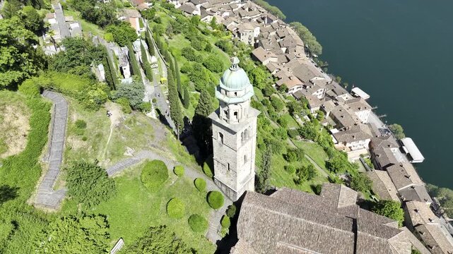 Aerial view of Santa Maria del Sasso church tower in Morcote, Lake Lugano, Switzerland. Drone tilt up reveal.