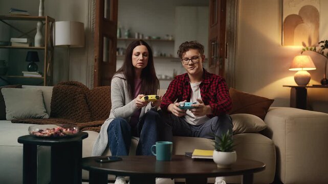 Teen son teaching his mom how to use a gamepad, playing video games together