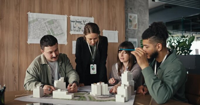 Group meets to discuss project details in an office with models and maps. Ideas are shared and plans are developed