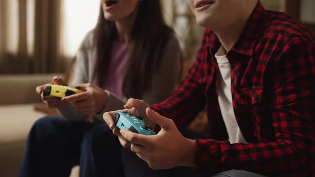 Joyful mom and her adolescent son playing video games with gamepads, having fun