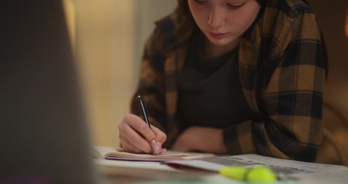 Young woman writing notes in a notebook at a desk
