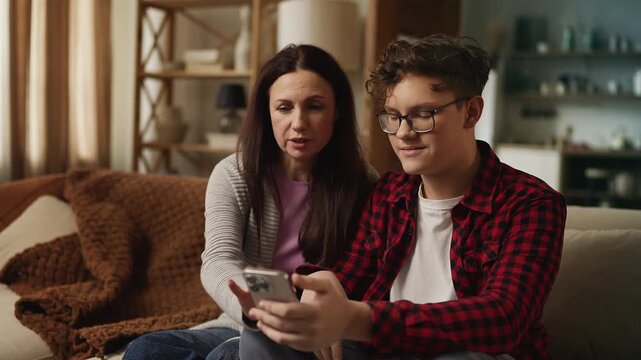 Teenage son explaining to his mother how to use a photo editing app on phone