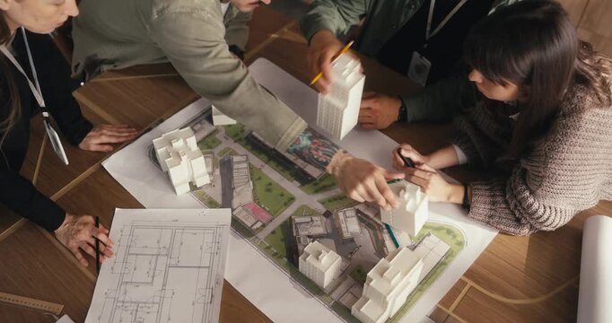 Team discussing a building model with floor plans in office