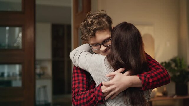 Happy teenage son hugging his mother after returning home from university