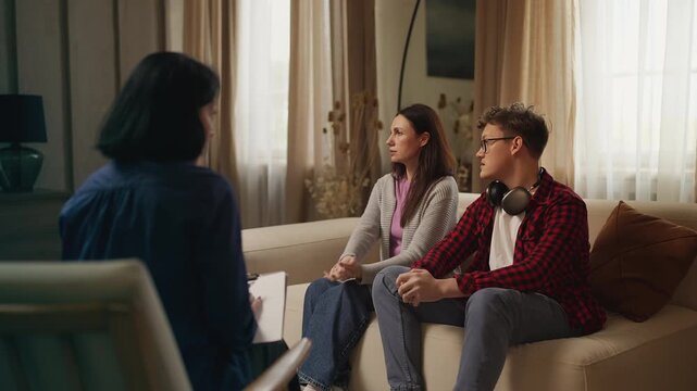 Nervous teenage boy and his mother talking with a teen psychologist, therapy