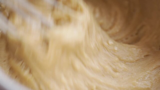 Mixing thick cake batter, with metal whisk moving through smooth mixture. Concept of baking recipe, dessert preparation and cake making