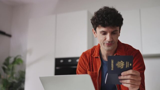 Focused man holding U.S. passport while booking flight tickets on laptop