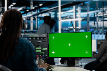 Obraz premium Data center engineer uses a green screen computer in a data center for server operations, screen replacement, and server workflow monitoring.