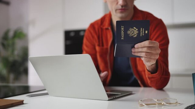 Man holding U.S. passport while booking hotel on laptop, travel planning