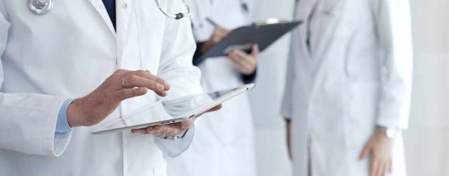 Healthcare professional using a digital tablet for patient data management, doctors collaborating on medical records, modern clinic team focusing on health technology