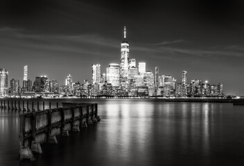 Fototapeta premium Black and white long exposure of the Lower Manhattan skyline and World Trade Center skyscrapers reflected in the Hudson River at night, New York City, USA