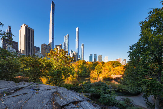 Central Park autumn foliage and rock formations with view of Billionaires' Row supertall skyscrapers. Midtown Manhattan, New York City