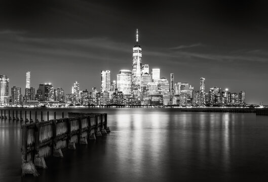 Black and white long exposure of the Lower Manhattan skyline and World Trade Center skyscrapers reflected in the Hudson River at night, New York City, USA