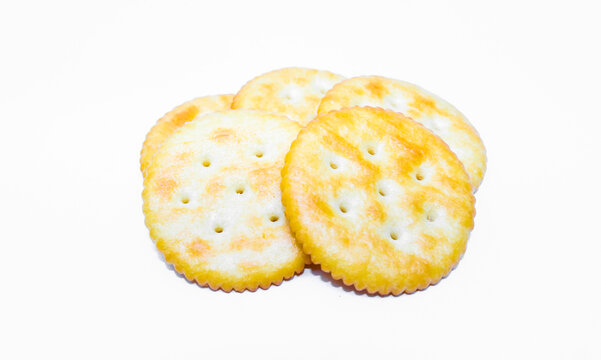 Many round salty crackers isolated on a white background. Top view crispy baked biscuit snack with golden texture. Delicious snacks. Round salted cracker biscuits.